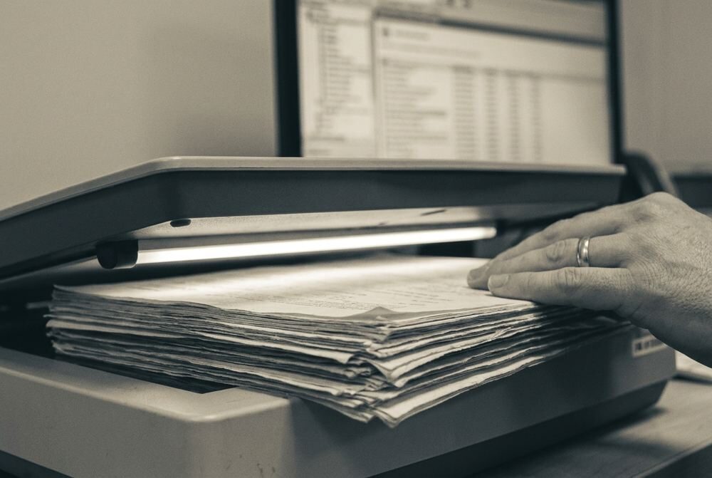 A scanner mid-pass over a stack of mixed paper documents